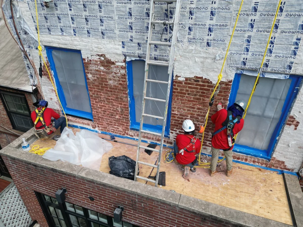 Elite Waterproofing crew waterproofing a brick building facade in Long Island, NY